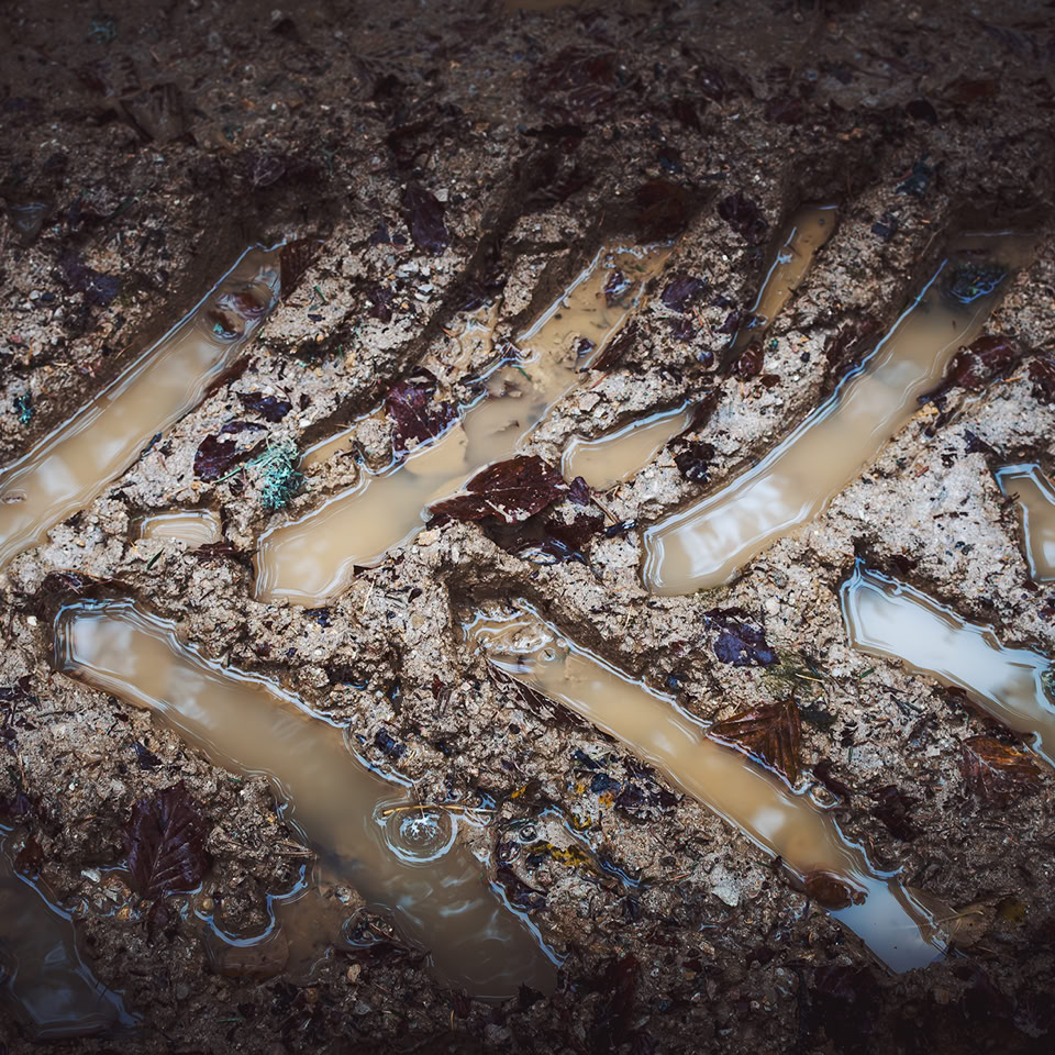 Empreinte de pneu dans la boue avec de l'eau stagnante.
