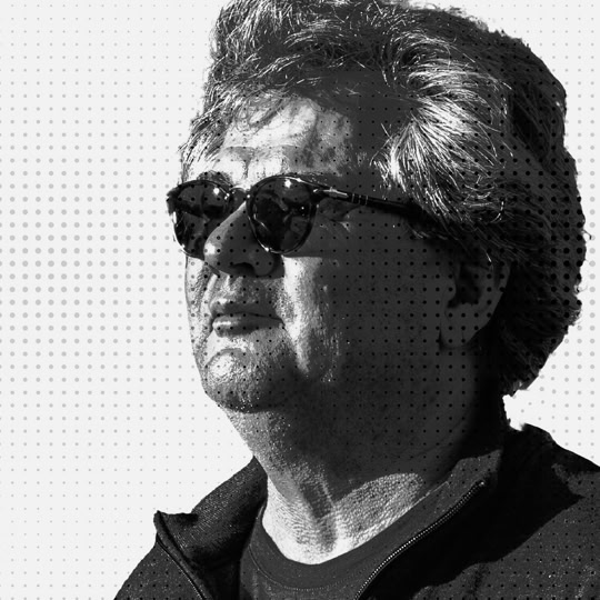 Homme portant des lunettes de soleil, regardant vers la gauche, en noir et blanc. André Ruprecht, graphiste, photographe.