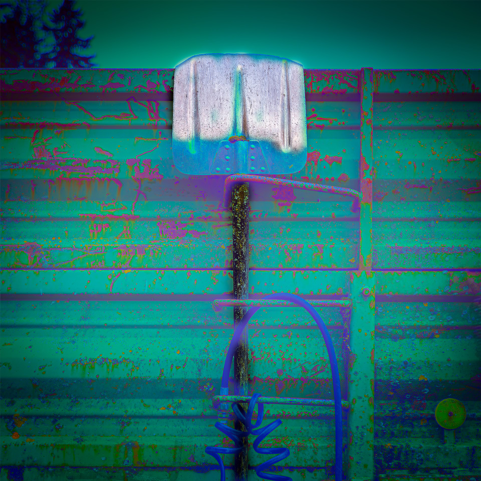 Une pelle métallique accrochée à une clôture en bois colorée.